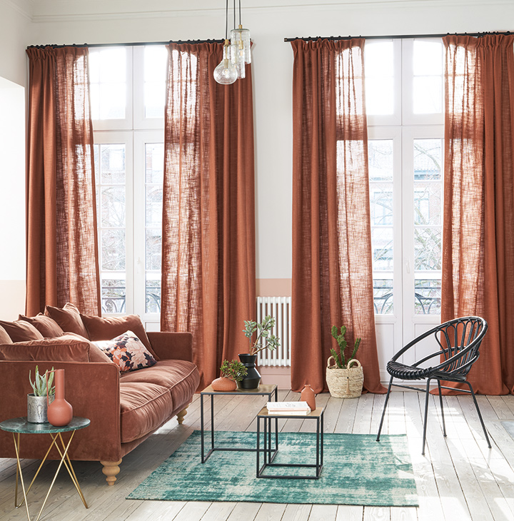 Rideaux et voilages sur mesure à Saint-Étienne & Montbrison : l’art de la finition parfaite 1 Rideaux sur mesure en lin terracotta dans un salon lumineux avec parquet