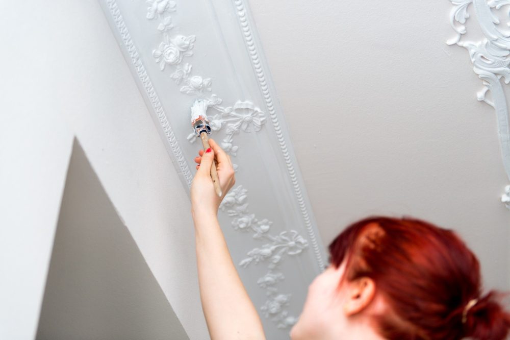 Application peinture de finition au pinceau sur moulures de plafond ancien rénovation à Saint-Étienne